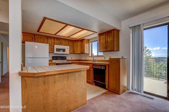 kitchen with tile counters, a peninsula, brown cabinetry, white appliances, and a sink