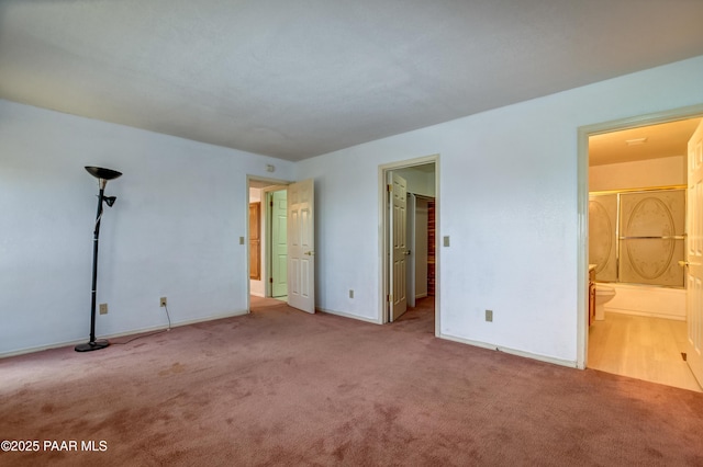 unfurnished bedroom with ensuite bathroom, baseboards, and carpet floors