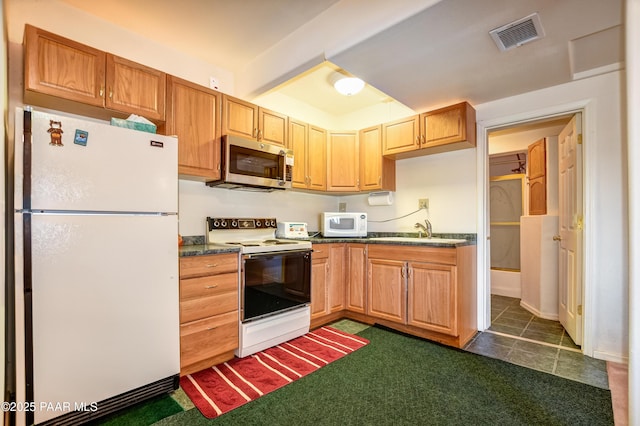 kitchen featuring white appliances, visible vents, a sink, dark countertops, and dark colored carpet