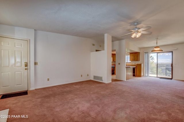 unfurnished living room featuring a ceiling fan, light colored carpet, visible vents, and baseboards