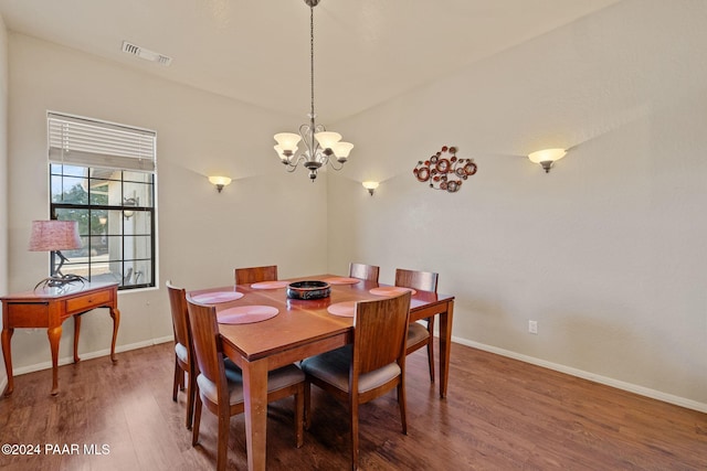 dining room with dark hardwood / wood-style floors and an inviting chandelier