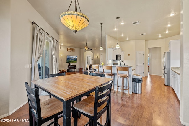 dining area featuring ceiling fan, light wood-type flooring, and sink