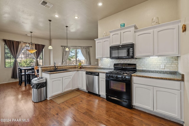 kitchen with dark hardwood / wood-style floors, white cabinets, black appliances, and decorative light fixtures