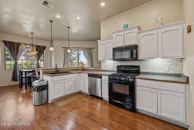 kitchen with dark hardwood / wood-style floors, white cabinets, black appliances, and decorative light fixtures