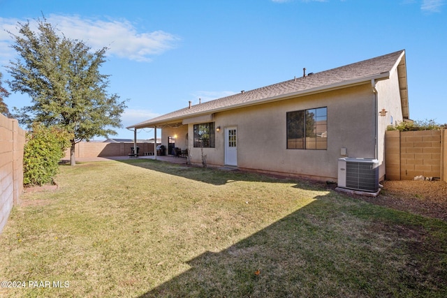 back of property with a lawn and central AC