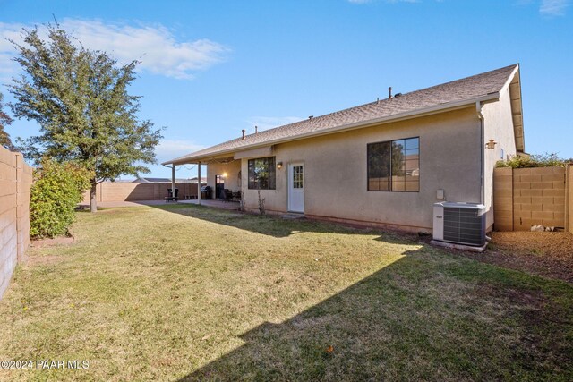 back of property with a lawn and central AC