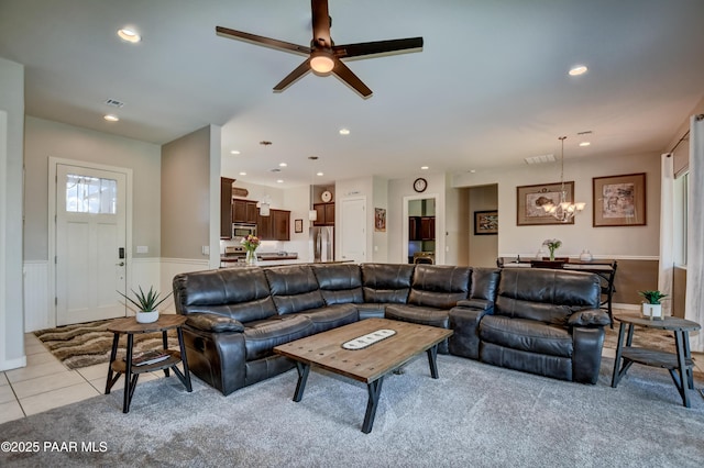 living area featuring recessed lighting, light tile patterned floors, ceiling fan with notable chandelier, and a wainscoted wall