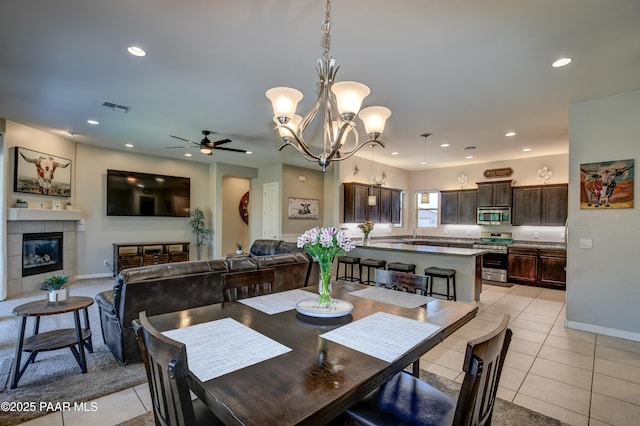 dining room featuring visible vents, a tile fireplace, light tile patterned floors, ceiling fan with notable chandelier, and recessed lighting