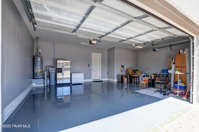 garage featuring stainless steel fridge, baseboards, a garage door opener, and gas water heater