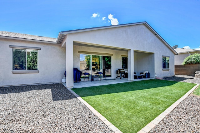 rear view of property with a lawn, a patio area, fence, outdoor lounge area, and stucco siding