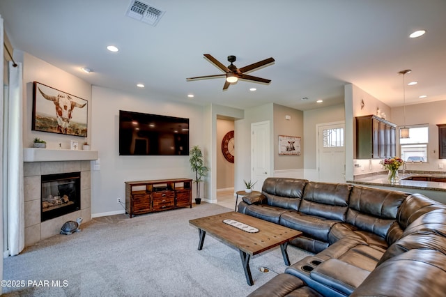 carpeted living room with recessed lighting, ceiling fan, visible vents, and a tile fireplace