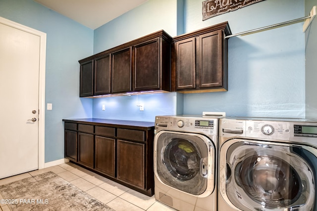 laundry area featuring light tile patterned floors, cabinet space, and washing machine and clothes dryer