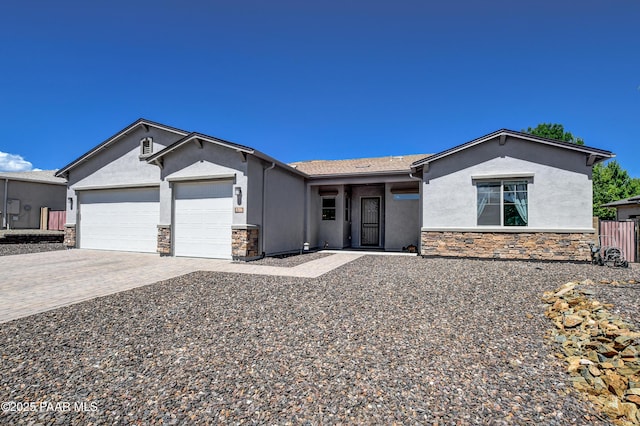 ranch-style home featuring a garage, stucco siding, decorative driveway, and stone siding