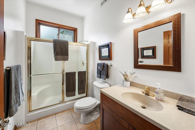 bathroom with tile patterned floors, vanity, toilet, and an enclosed shower