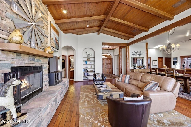 living room with hardwood / wood-style flooring, a stone fireplace, high vaulted ceiling, and a chandelier