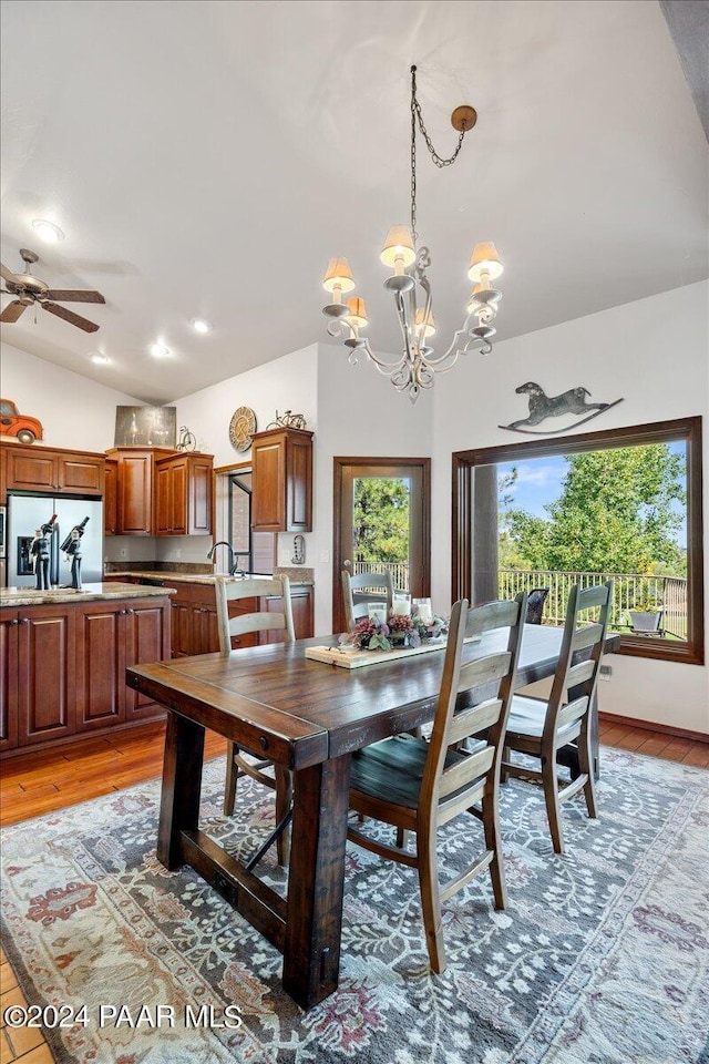 dining area featuring plenty of natural light, light wood-type flooring, ceiling fan with notable chandelier, and vaulted ceiling