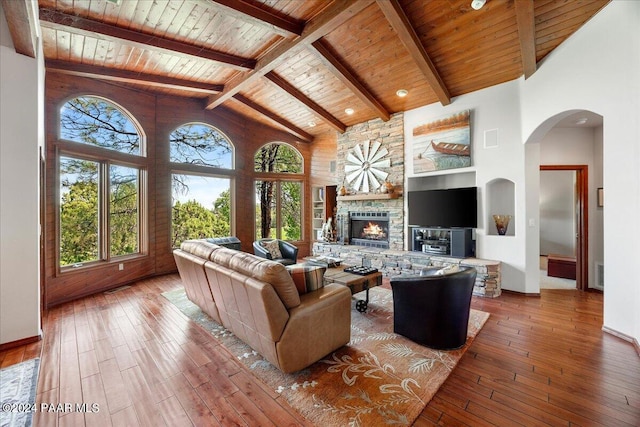 living room featuring hardwood / wood-style floors, a stone fireplace, wooden ceiling, and high vaulted ceiling