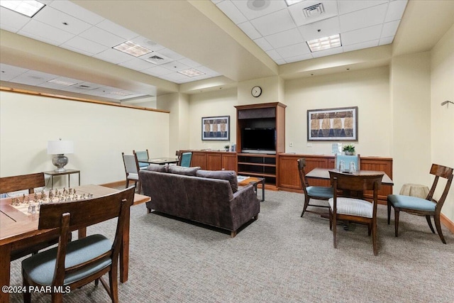 carpeted living room featuring a drop ceiling