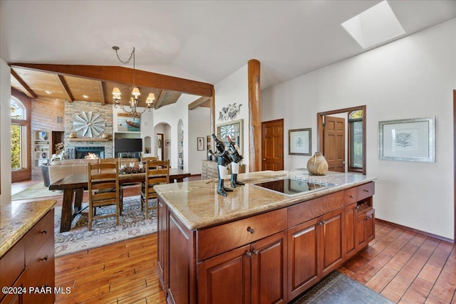 kitchen with hardwood / wood-style floors, a center island, a stone fireplace, and hanging light fixtures