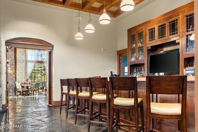 bar with beamed ceiling, pendant lighting, and coffered ceiling