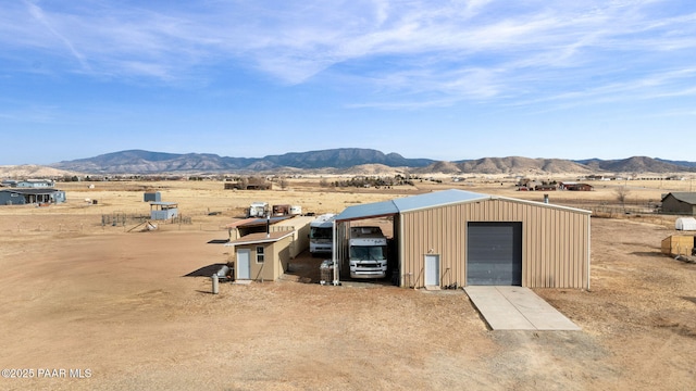 view of outdoor structure with a mountain view, a rural view, and a garage