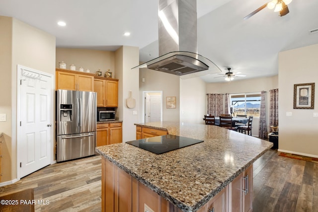 kitchen featuring a spacious island, ceiling fan, appliances with stainless steel finishes, stone countertops, and island range hood