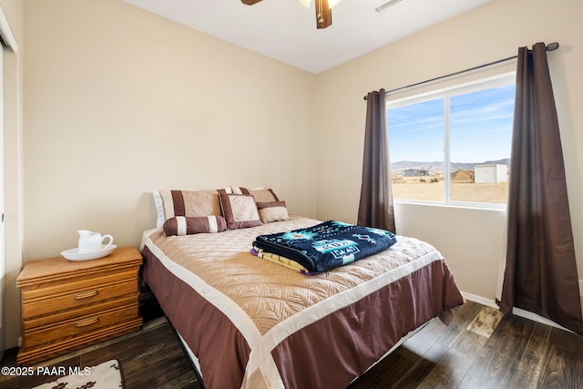 bedroom with ceiling fan, dark hardwood / wood-style flooring, and a mountain view