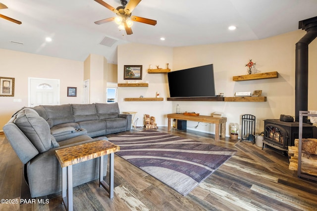 living room with hardwood / wood-style flooring, lofted ceiling, ceiling fan, and a wood stove