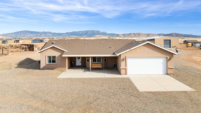 ranch-style home with a mountain view, a patio, and a garage