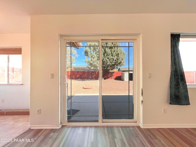 doorway with wood finished floors and baseboards