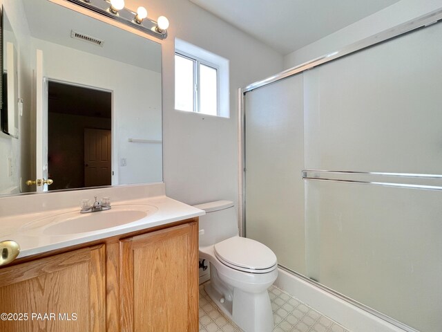 full bathroom featuring toilet, vanity, visible vents, tile patterned floors, and a stall shower