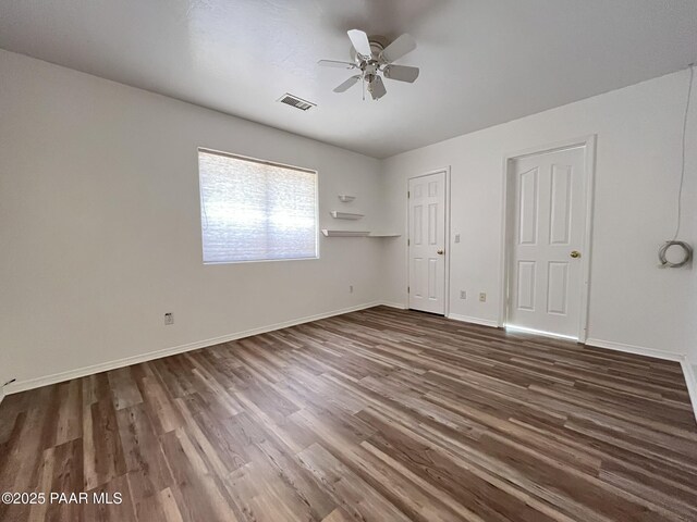 unfurnished bedroom with a ceiling fan, dark wood-style flooring, visible vents, and baseboards