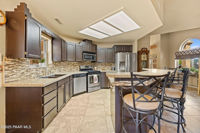 5278 N Saddleback Dr, Prescott Valley, AZ 86314 - kitchen featuring decorative backsplash, a kitchen bar, appliances with stainless steel finishes, dark brown cabinets, and a sink