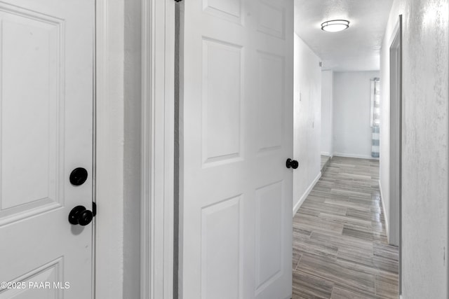 hall with a textured ceiling and light hardwood / wood-style flooring