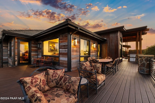 deck at dusk with outdoor lounge area and exterior kitchen