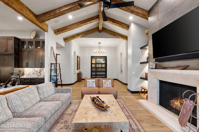 living room featuring ceiling fan with notable chandelier, lofted ceiling with beams, and light hardwood / wood-style flooring