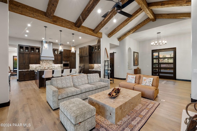 living room with beam ceiling, ceiling fan with notable chandelier, high vaulted ceiling, and light hardwood / wood-style flooring