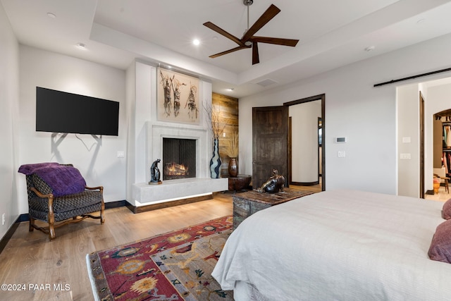 bedroom with hardwood / wood-style floors, a tray ceiling, and ceiling fan