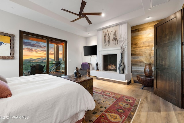 bedroom featuring a tray ceiling, access to exterior, ceiling fan, and light hardwood / wood-style floors