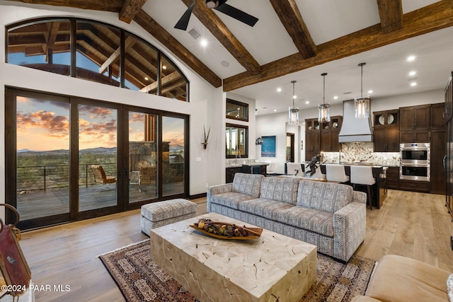 living room with beamed ceiling, ceiling fan, light wood-type flooring, and high vaulted ceiling