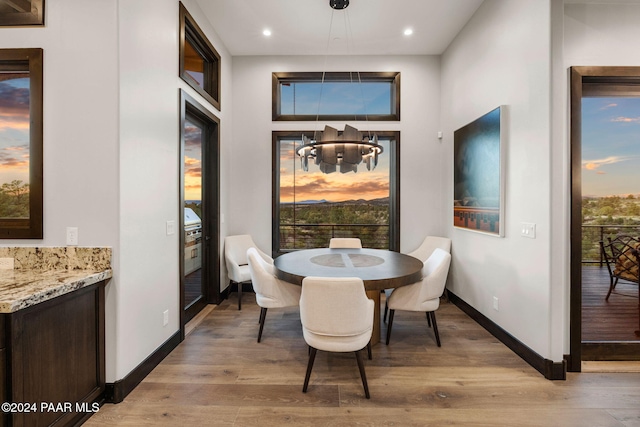 dining room with a healthy amount of sunlight, light hardwood / wood-style floors, and a notable chandelier