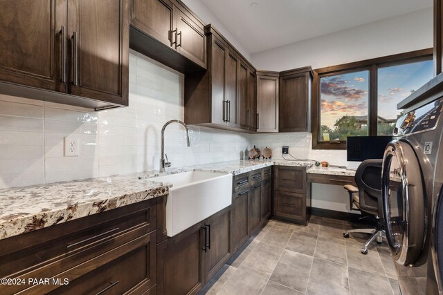 kitchen with decorative backsplash, light stone counters, dark brown cabinetry, sink, and built in desk