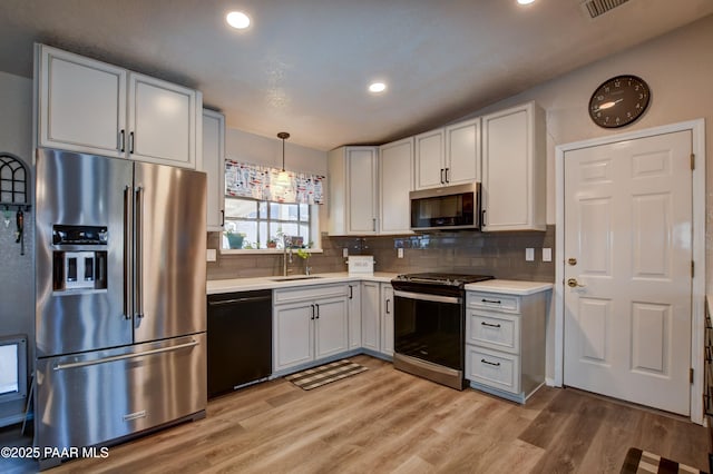 kitchen featuring stainless steel appliances, hanging light fixtures, sink, and white cabinets