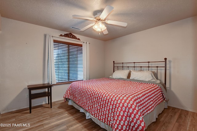 bedroom with light wood-type flooring, a textured ceiling, and ceiling fan