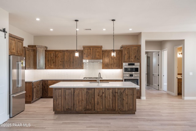 kitchen featuring stainless steel appliances, a sink, light countertops, decorative backsplash, and recessed lighting