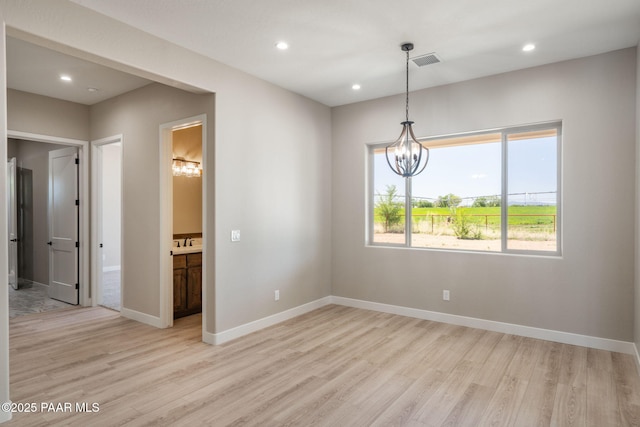 empty room featuring light wood-style flooring, a chandelier, recessed lighting, baseboards, and a sink