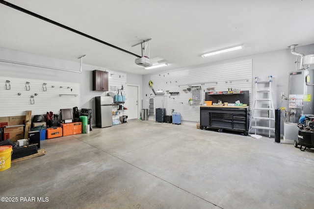 7921 E Las Palmas Dr, Prescott Valley, AZ 86314 - garage featuring freestanding refrigerator, gas water heater, a workshop area, and a garage door opener