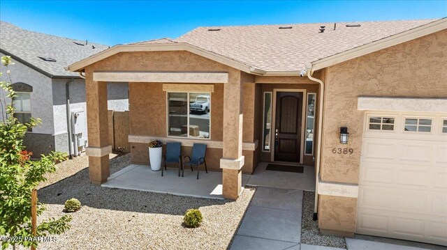 doorway to property featuring roof with shingles and stucco siding