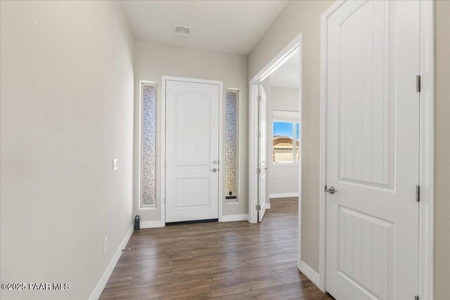 hallway featuring dark wood-type flooring, visible vents, and baseboards