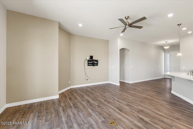 unfurnished living room with recessed lighting, a ceiling fan, arched walkways, and dark wood-type flooring